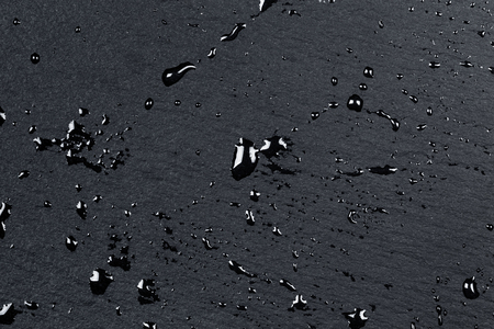 Water drops on dark stone surface of basalt or graniteの写真素材