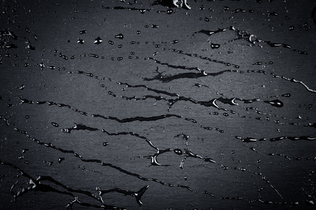 Water drops on dark stone surface of basalt or graniteの写真素材