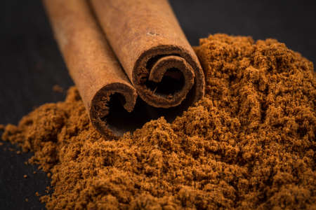 Cinnamon sticks with cinnamon powder on stone plate backgroundの写真素材