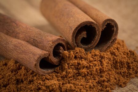 Cinnamon sticks with cinnamon powder on wooden backgroundの写真素材