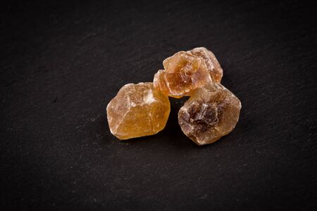 caramelized candy brown sugar on a dark stone boardの写真素材