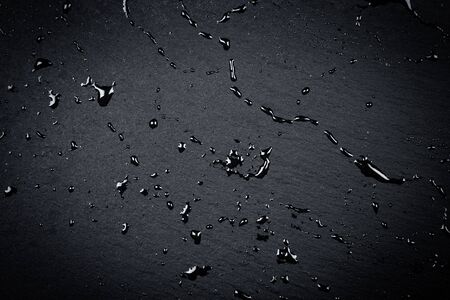 Water drops on dark stone surface of basalt or graniteの写真素材