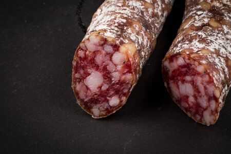 slices of salami on a dark stone board as a background