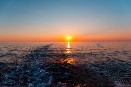 Sunset in the sea and a trace from the shipの写真素材