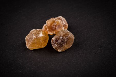 caramelized candy brown sugar on a dark stone boardの写真素材