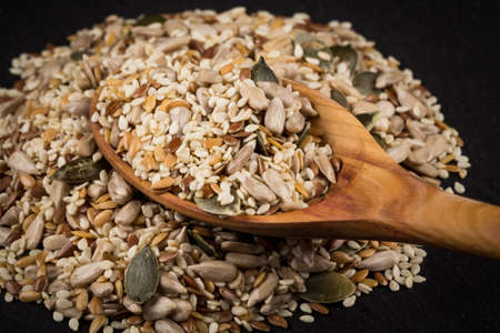 Healthy seeds mix in a wooden spoon on stone backgroundの写真素材