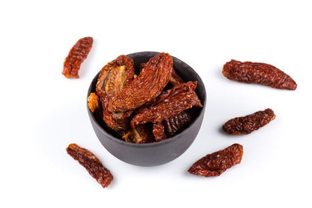 dried tomatoes in stone bowl close up on white backgroundの写真素材