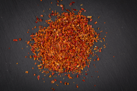Crushed red chili pepper on dark stoneの写真素材