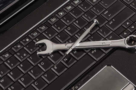 wrench tool and screwdrivers over a laptop, repair service conceptの写真素材