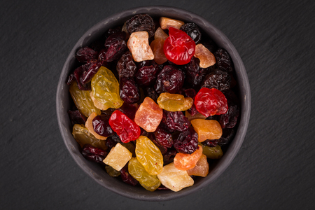 Mix variety of dried fruit in bowl over black dark stone backgroundの写真素材