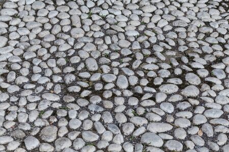 Round stones in the ground. Texture of the cobblestones in Park. Paved road for pedestrians. The...