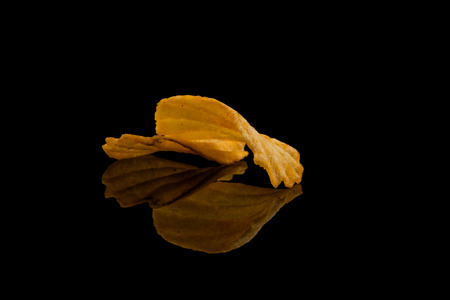 Potato chip on black surface closeup reflection detail
