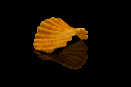 Potato chip on black surface closeup reflection detail