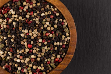 bowl of various pepper peppercorns seeds mix on black stone