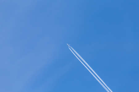 Shot of long trail of jet plane on blue skyの写真素材