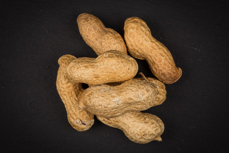 Raw peanuts shells over dark stone backgroundの写真素材
