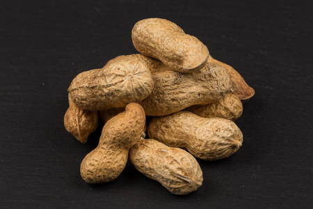 Raw peanuts shells over dark stone background