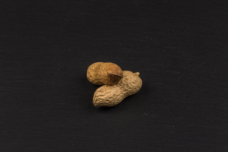 Raw peanuts shells over dark stone background