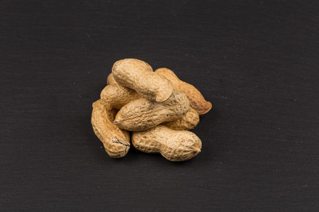Raw peanuts shells over dark stone background