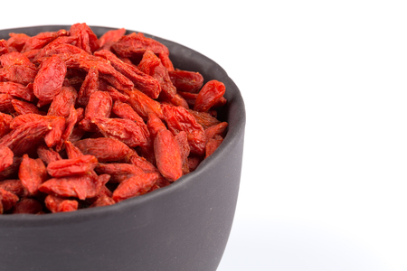 Chinese goji berries in dark stone bowl close up on white backgroundの写真素材