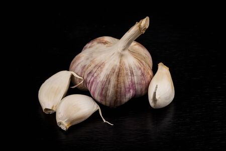 Garlic bulb closeup isolated on dark stone backgroundの写真素材