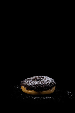 Sprinkling sugar powder on delicious donut topped with chocolateの写真素材