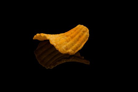 Potato chip on black surface closeup reflection detail
