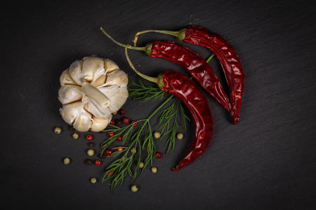Seasoning ingredients for cooking - spices, pepper mix, chili pepper, garlic, dill. Top view on stone plateの写真素材