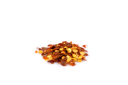 The pile of a crushed red pepper, dried chili flakes and seeds isolated on white background