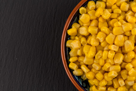 sweet canned corn in bowl on darl black stone slate board