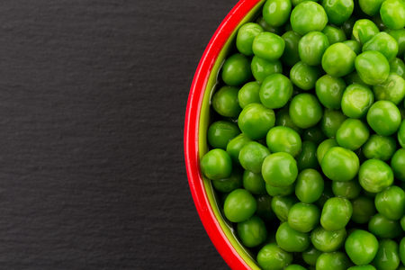 Bowl of green wet pea isolated on dark stone backgroundの写真素材