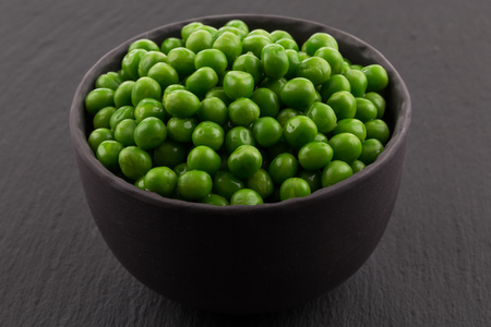 Bowl of green wet pea isolated on dark stone backgroundの写真素材
