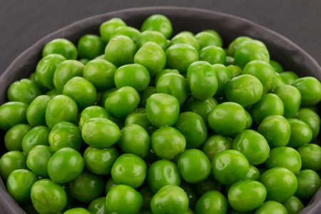 Bowl of green wet pea isolated on dark stone backgroundの写真素材