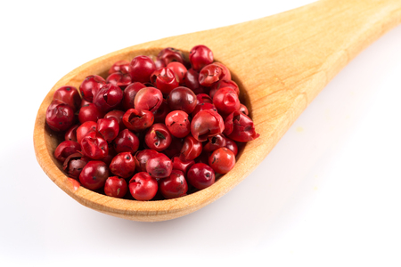 red spice pepper peppercorns in a spoon over whiteの写真素材