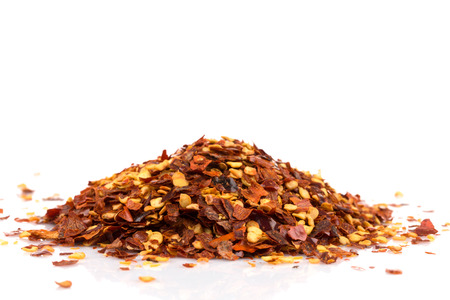 The pile of a crushed red pepper, dried chili flakes and seeds isolated on white backgroundの写真素材