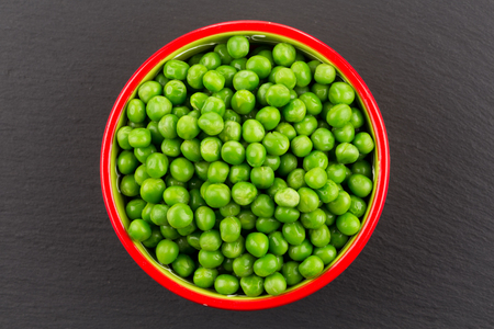 Bowl of green wet pea isolated on dark stone backgroundの写真素材