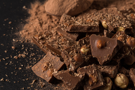 Broken chocolate nuts pieces and cocoa powder on dark stone backgroundの写真素材