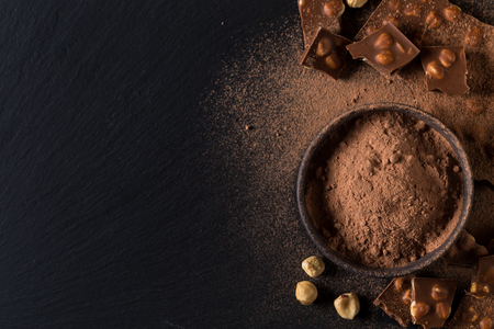 Broken chocolate nuts pieces and cocoa powder on dark backgroundの写真素材