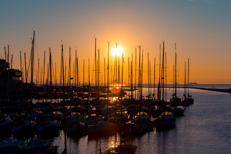 rows of boats at pier in the evening against sunset skies (sunset dusk lighting)の写真素材