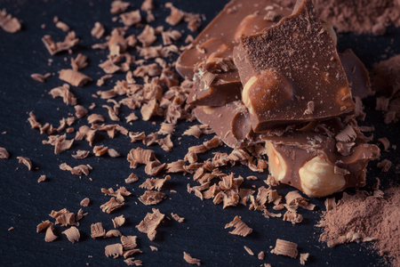 Broken chocolate nuts pieces and cocoa powder on dark backgroundの写真素材