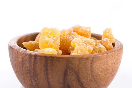 heap of sweat Candied ginger isolated on white background in wooden bowlの写真素材