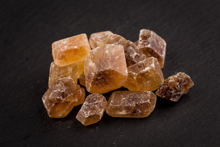 caramelized candy brown sugar on a dark stone boardの写真素材