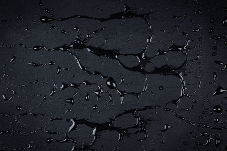 Water drops on dark stone surface of basalt or graniteの写真素材