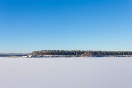 Frozen lake with ice and snow, sunny winter day. Forestの写真素材