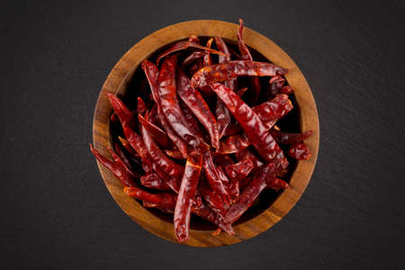 dried chili isolated on black background. In wooden bowl -closeup photoの写真素材