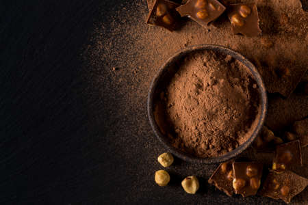 Broken chocolate nuts pieces and cocoa powder on dark backgroundの写真素材