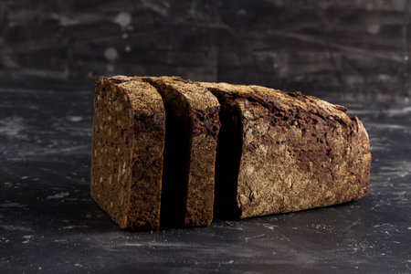 Rye black bread with seeds  on dark board background