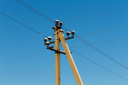 Power lines dripping with icicles against a clear blue skyの写真素材