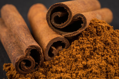 Cinnamon sticks with cinnamon powder on stone plate backgroundの写真素材