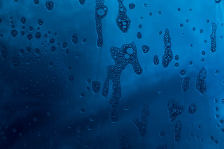 Blue texture with natural soap foam pattern on glassの写真素材